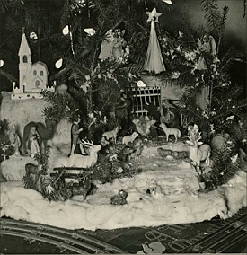 This is a detail from a photo on collector Ted Althof's site. Track for a Standard Gauge train is in the foreground, the Nativity is in the center right position and a Japanese pasteboard cathedral is at the left. You can also see C6 lightbulbs and 'icicles' made of lead foil. The photo probably dates between 1920 and 1939. Click to see the whole photo.