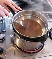 This 'double-broiler' ensures that the cholocate will never get above the boiling point of water, so it won't burn.  But it does increase the risk of splashing water into the chocolate, a very bad thing. Click for bigger photo.